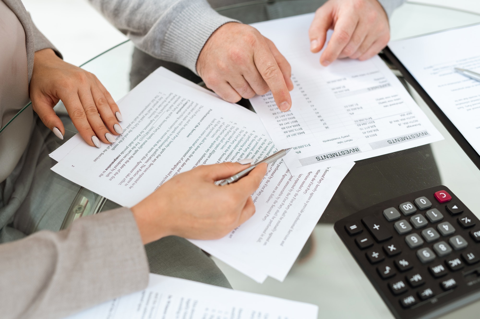 Hands of agent and mature man pointing at financial documents